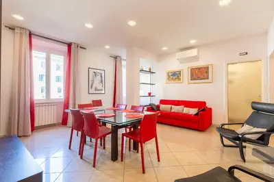 a living room with a table and chairs and a red couch at Lungotevere Aventino House by ACS HOLIDAYS in Rome