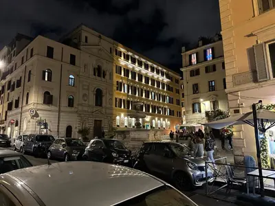 a city street with parked cars and buildings at night at IMPERIAL suite COLOSSEUM in Rome