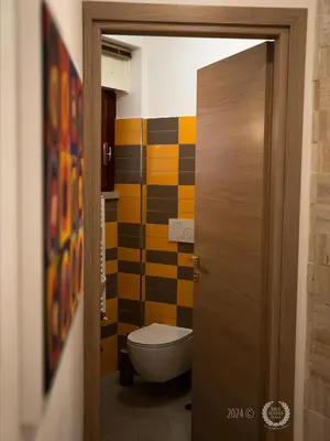 a bathroom with a toilet and a colorful wall at DeaSuites One in Rome