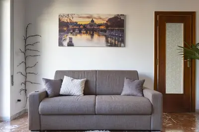 a couch in a living room with a painting on the wall at The Roma Flat- private parking & direct bus to Vatican City in Rome