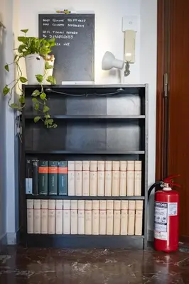 a book shelf filled with books next to a fire extinguisher at The Roma Flat- private parking & direct bus to Vatican City in Rome