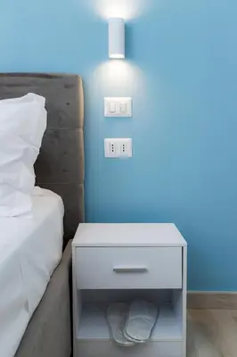 a white nightstand next to a bed with a blue wall at Green Garden in Rome
