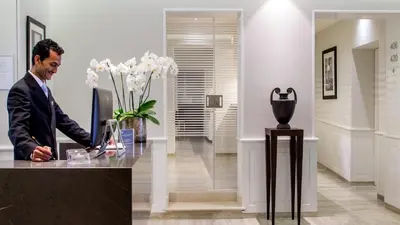a man in a suit standing at a counter in a lobby at Princeps Boutique Hotel in Rome