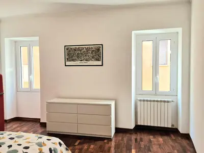 a white bedroom with a dresser and two windows at appartamento monticiano in Rome