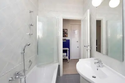 a white bathroom with a sink and a mirror at Bright Vatican 2 bedroom Apartment in Rome