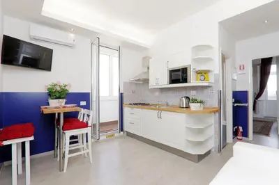 a kitchen with white cabinets and a blue wall at Bright Vatican 2 bedroom Apartment in Rome