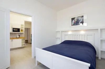 a white bedroom with a bed and a kitchen at Bright Vatican 2 bedroom Apartment in Rome