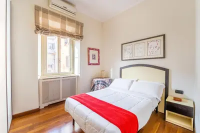 a bedroom with a large white bed with a red blanket at Dimora Esedra, Historical Flat in the Heart of Rome in Rome