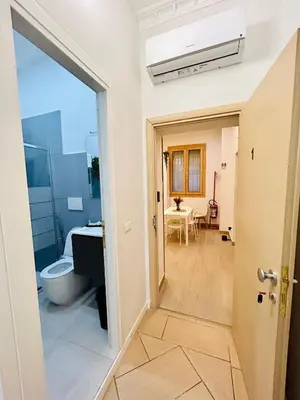 a hallway leading to a bathroom with a toilet and a table at Domus Giolitti in Rome
