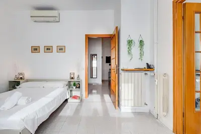 a white bedroom with two beds and a hallway at Casa San Paolo in Rome