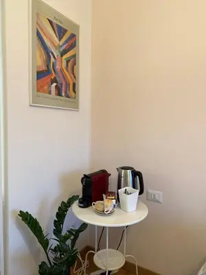 a table with a coffee maker on it next to a painting at San Paolo Corner in Rome