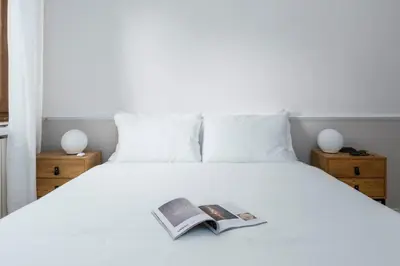 a bedroom with a white bed with a book on it at Zen Vatican Studio - Zen 30 in Rome