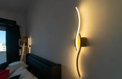 a light on a wall next to a bed at Aim - La Cupola - Saint Peter view apartment in Rome