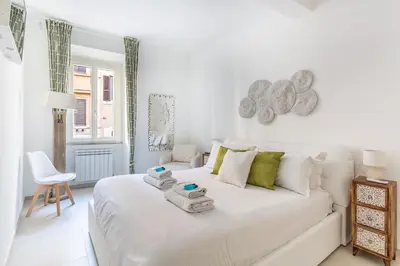 a white bedroom with a white bed and a chair at Iflat New Cozy Retreat Near the Colosseum in Rome