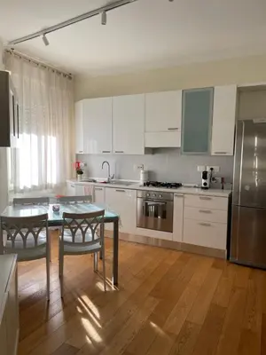 a kitchen with white cabinets and a table with chairs at Casetta via delle Cave in Rome