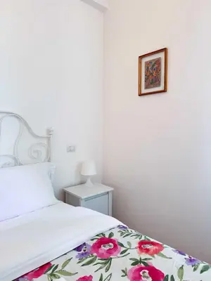 a white bedroom with a bed with a floral blanket at Piramide Suites 2 Bedrooms & 2 Bathrooms in Rome