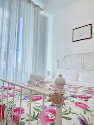 a white bedroom with a bed with a flower blanket at Piramide Suites 2 Bedrooms & 2 Bathrooms in Rome