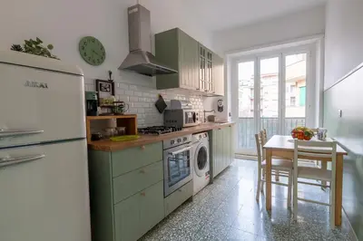 a kitchen with green cabinets and a table and a refrigerator at Olimpia House - Gianicolense in Rome