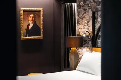 a bedroom with a portrait of a man in a suit at The Goethe Hotel - Small Luxury Hotels of the World in Rome