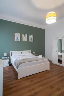 a bedroom with a large white bed and blue walls at Flower Fields Home - Appartamento Campo dei Fiori in Rome