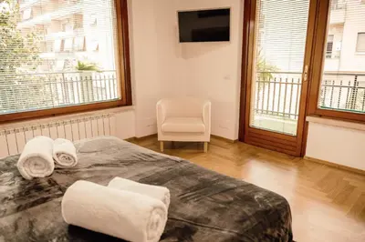 a bedroom with a bed and a chair and windows at Dea Suites Two in Rome