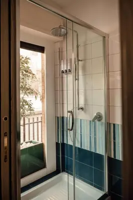 a bathroom with a shower with a glass door at Dea Suites Two in Rome