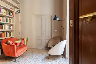 a living room with a chair and a book shelf at GuestHost - Central and Modern apartment in Rione Monti in Rome