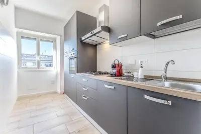 a kitchen with white cabinets and a sink and a window at Green House Marconi in Rome