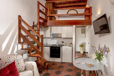 a small kitchen with a spiral staircase in a living room at Empire Loft in the shadow of Colosseum in Rome