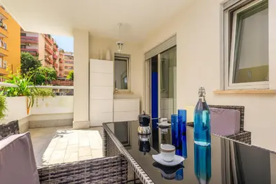 a glass table with blue vases on a balcony at Easylife - Vatican Terrace Apartment in Rome