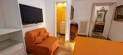 a living room with an orange chair and a flat screen tv at Machiavelli Forty Seven in Rome