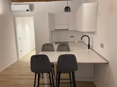 a kitchen with a counter with two chairs and a sink at Manzoni bilocale con doppi servizi piano terra in Rome