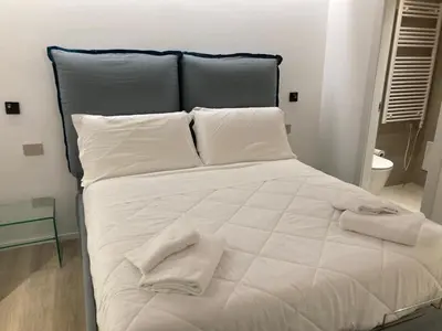 a large white bed with two towels on it at Manzoni bilocale con doppi servizi piano terra in Rome