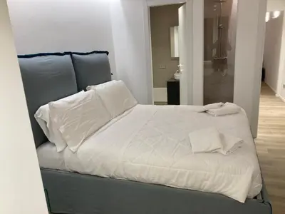 a bed with white sheets and pillows in a room at Manzoni bilocale con doppi servizi piano terra in Rome