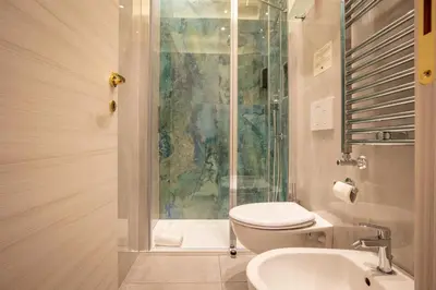a bathroom with a shower and a toilet and a sink at Twins Royal Suite in Rome