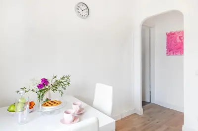 a white room with a table with flowers and a clock at Luxury Pink apartment in Rome