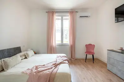 a bedroom with a bed and a window and a red chair at Luxury Pink apartment in Rome