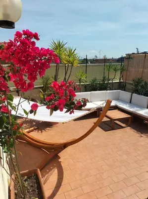 a patio with a table with red flowers on it at Amazing studio with terrace in Rome