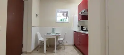 a small kitchen with a table and white chairs at Roma Brancaleone Loft, Metro C in Rome