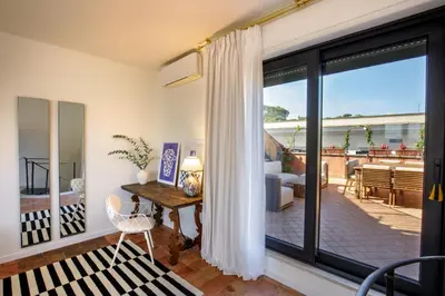 a living room with a large sliding glass door with a desk at Tiberim Lux Penthouse City View in Rome