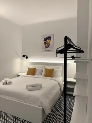 a white bedroom with a white bed with a black rack at Monti Elite House in Rome