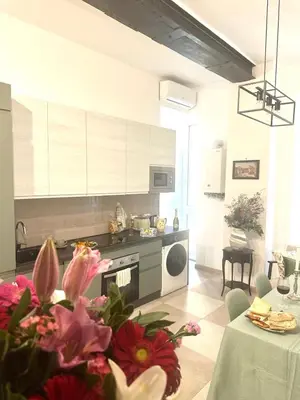 a kitchen with white cabinets and a table with flowers at The Prince Suite in Rome