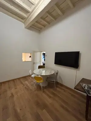 a room with a table and a tv on a wall at L'Arte Dei Sogni Apartment With Terrace- Trastevere District in Rome