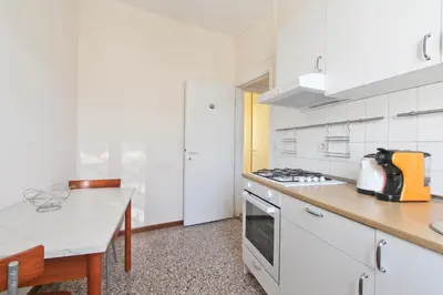 a kitchen with white cabinets and a table and a stove at Julia Apartment in Rome