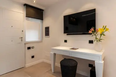a white desk with a television on a wall at JOIVY Borghese Luxury Suite in Rome