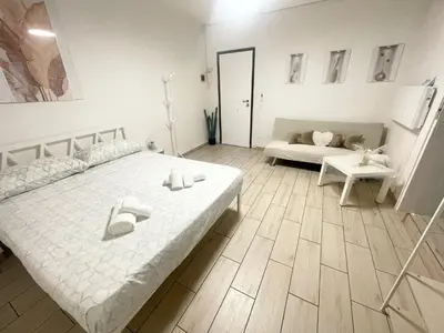 a white bedroom with a bed and a couch at Vicolo 17 in Rome