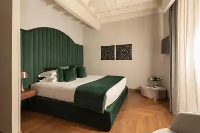 a bedroom with a large bed with a green headboard at pantheon suite 11 in Rome