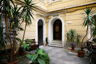 a building with palm trees and a bench in a courtyard at Cola di Rienzo Inn in Rome