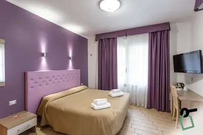 a bedroom with a bed with purple walls and a tv at HOTIDAY Room Collection - Roma Barberini in Rome