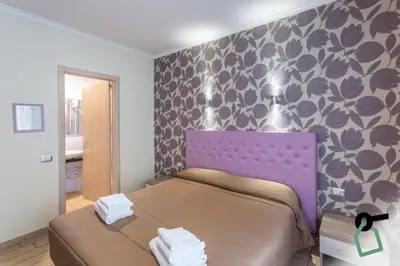 a bedroom with a bed with a purple head board at HOTIDAY Room Collection - Roma Barberini in Rome